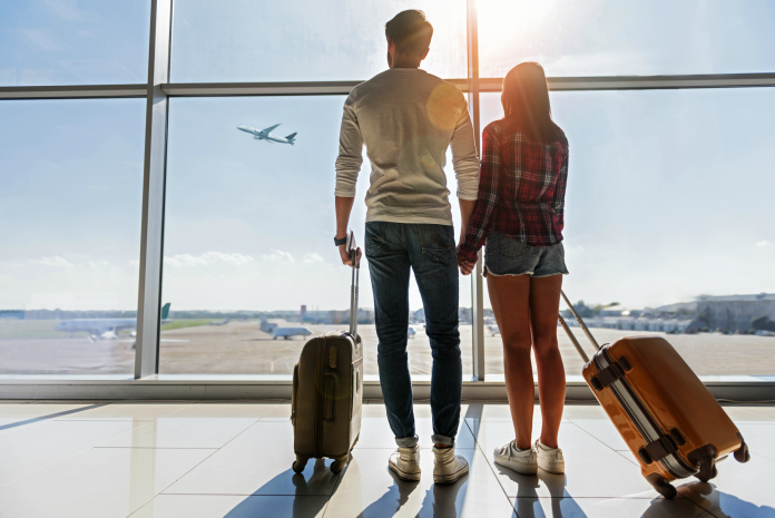 couple holding hands and looking out onto a runway